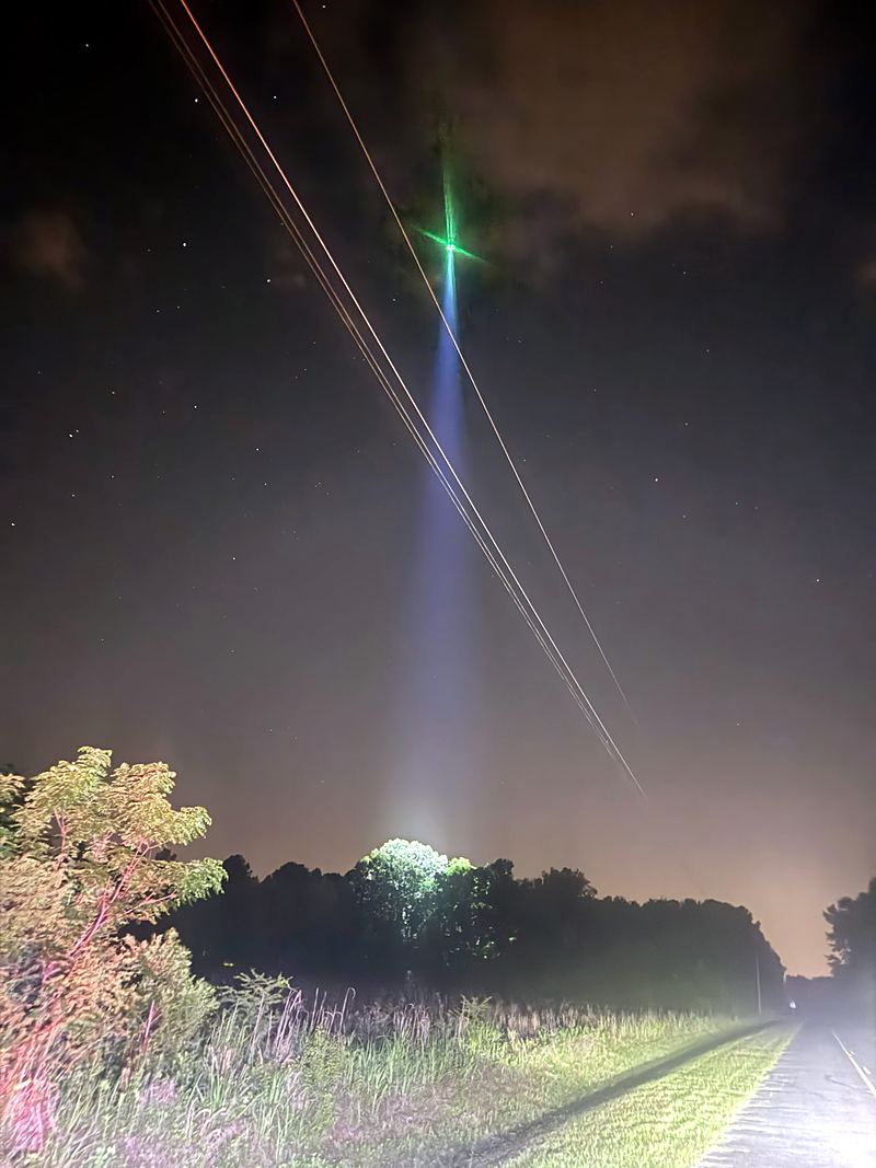 The drone's spotlight cutting through the dark over a field