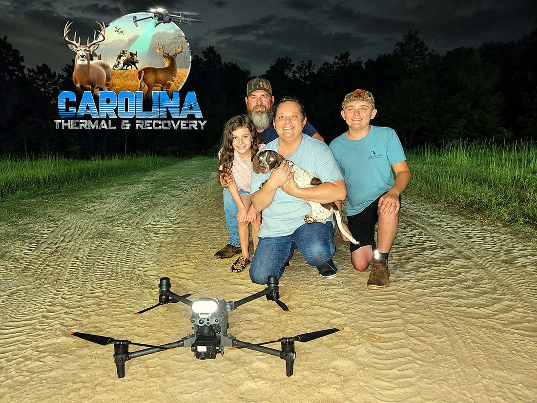 A family reunited with their dog at night, the thermal drone parked in front of them